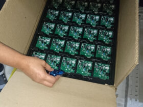 Ein MSR145 Datenlogger wird – nach dem Starten der Aufzeichnung per Knopfdruck – in einem Karton zusammen mit den bestückten Leiterplatten verpackt.